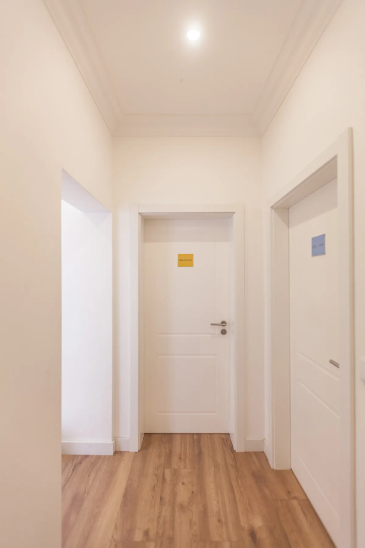A bright interior hallway with light wood flooring and several doorways.