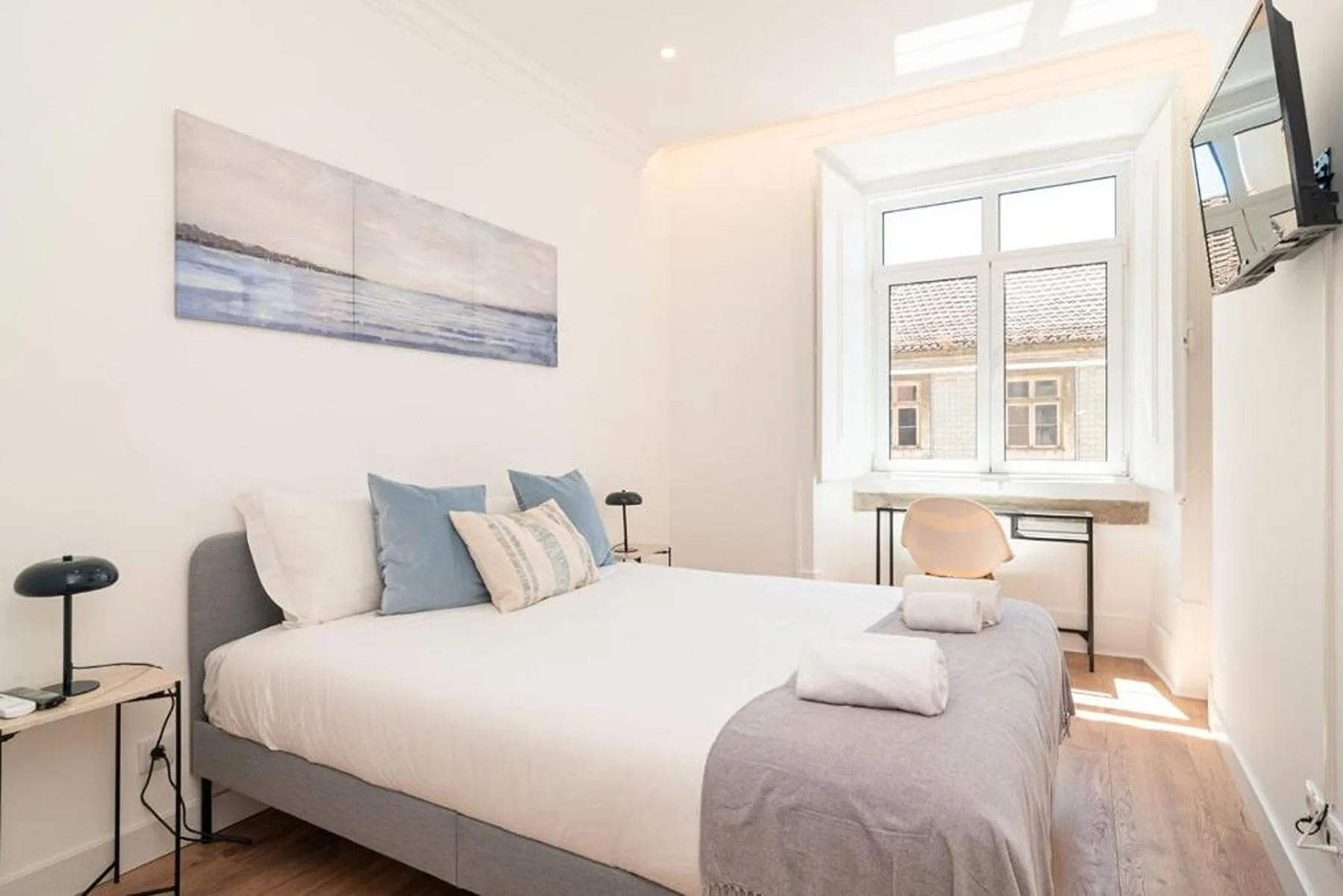 A bright bedroom with a neatly made bed and a window.