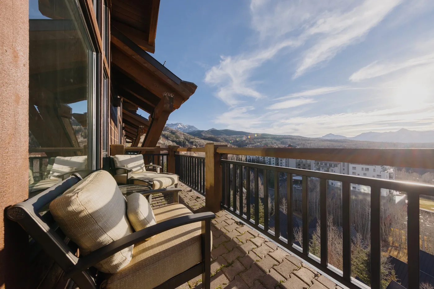 A balcony seating area overlooks a broad mountain valley.