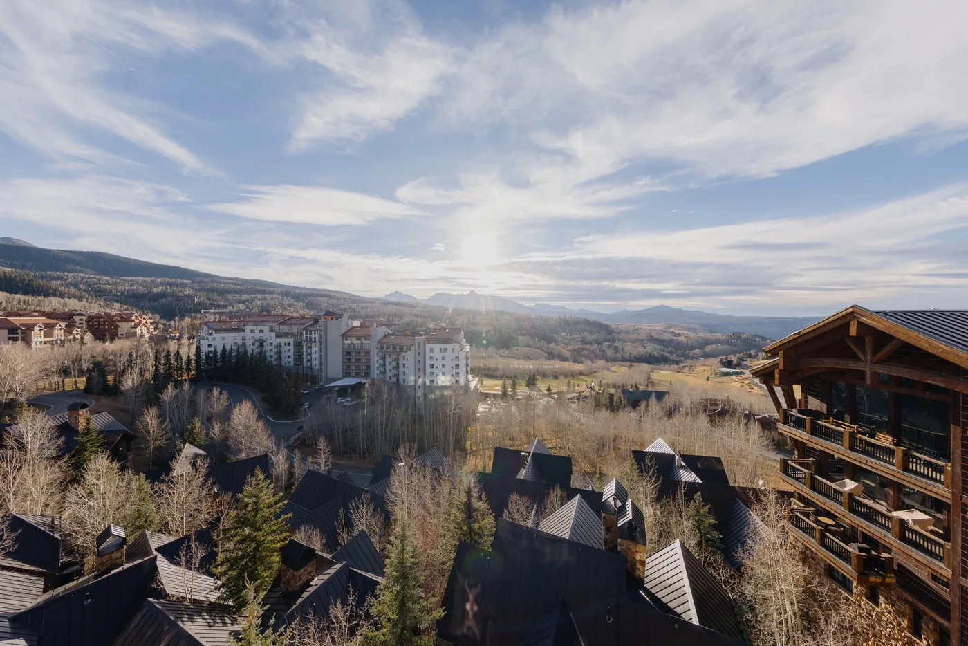 A hillside town and surrounding wooded hills sit beneath a broad, cloudy sky.