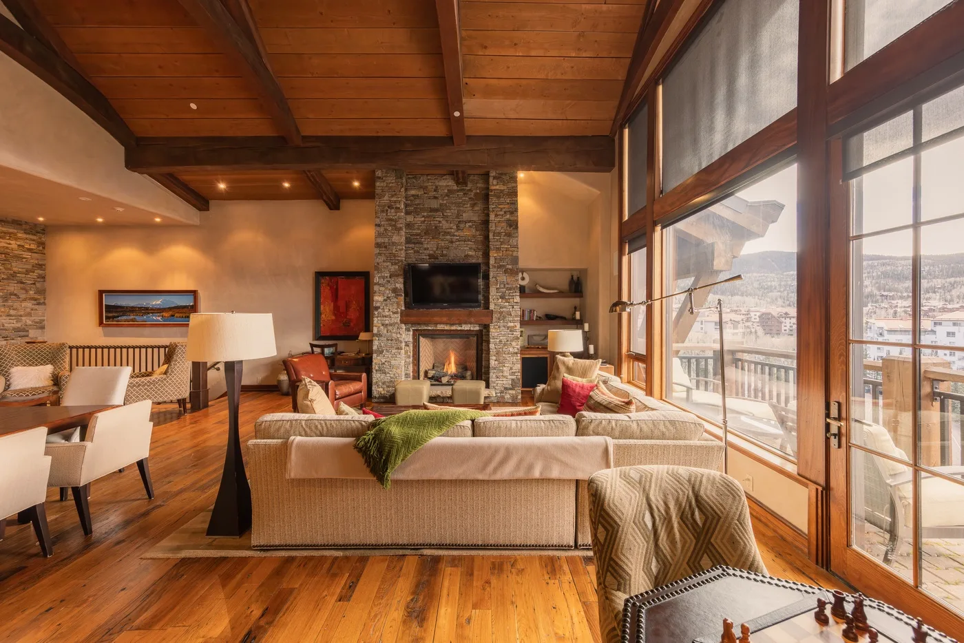 A living room with seating, a stone fireplace, and large windows overlooking the city.