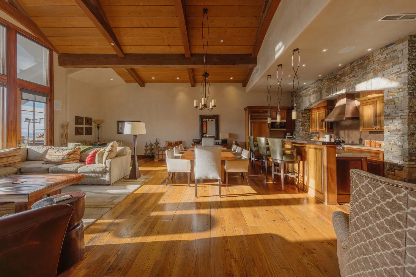 An open living and dining area with a kitchen and exposed wooden ceiling.