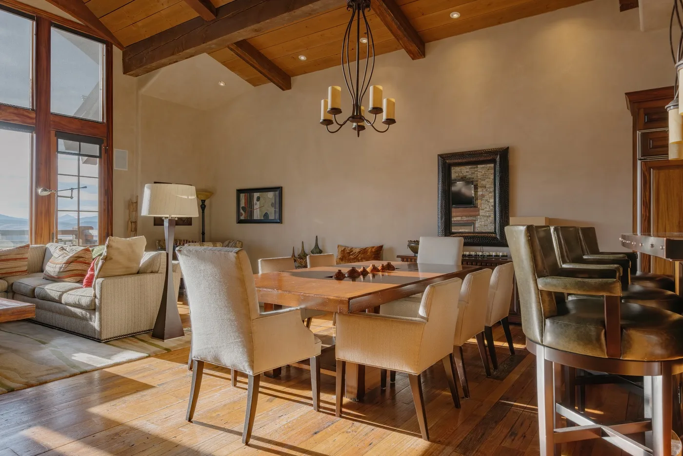 A dining and living area with a wooden table beneath exposed ceiling beams.