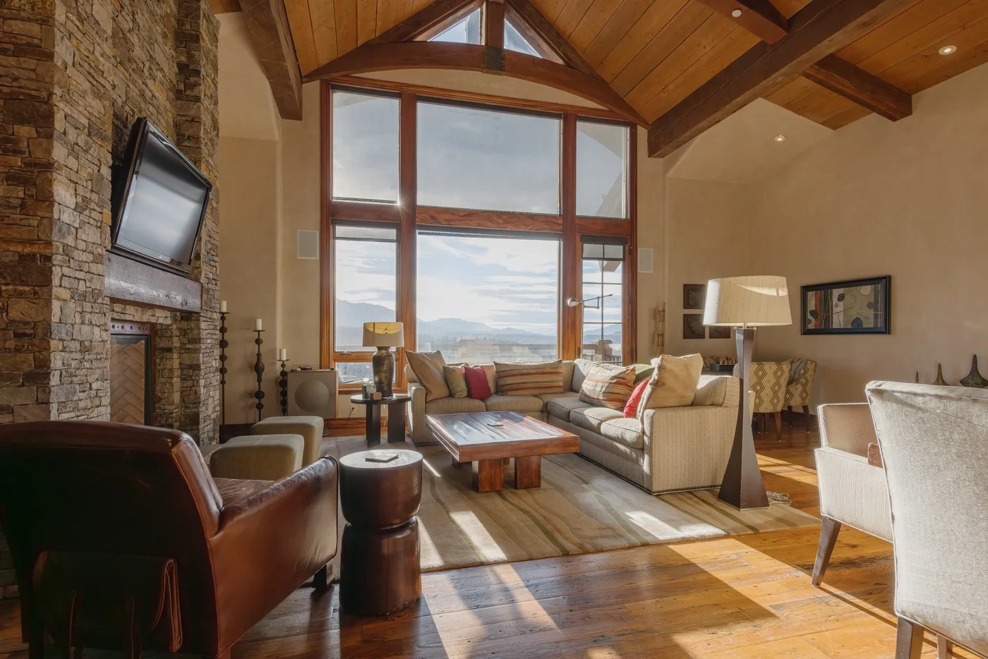 A living room with seating arranged around a coffee table beneath tall windows.