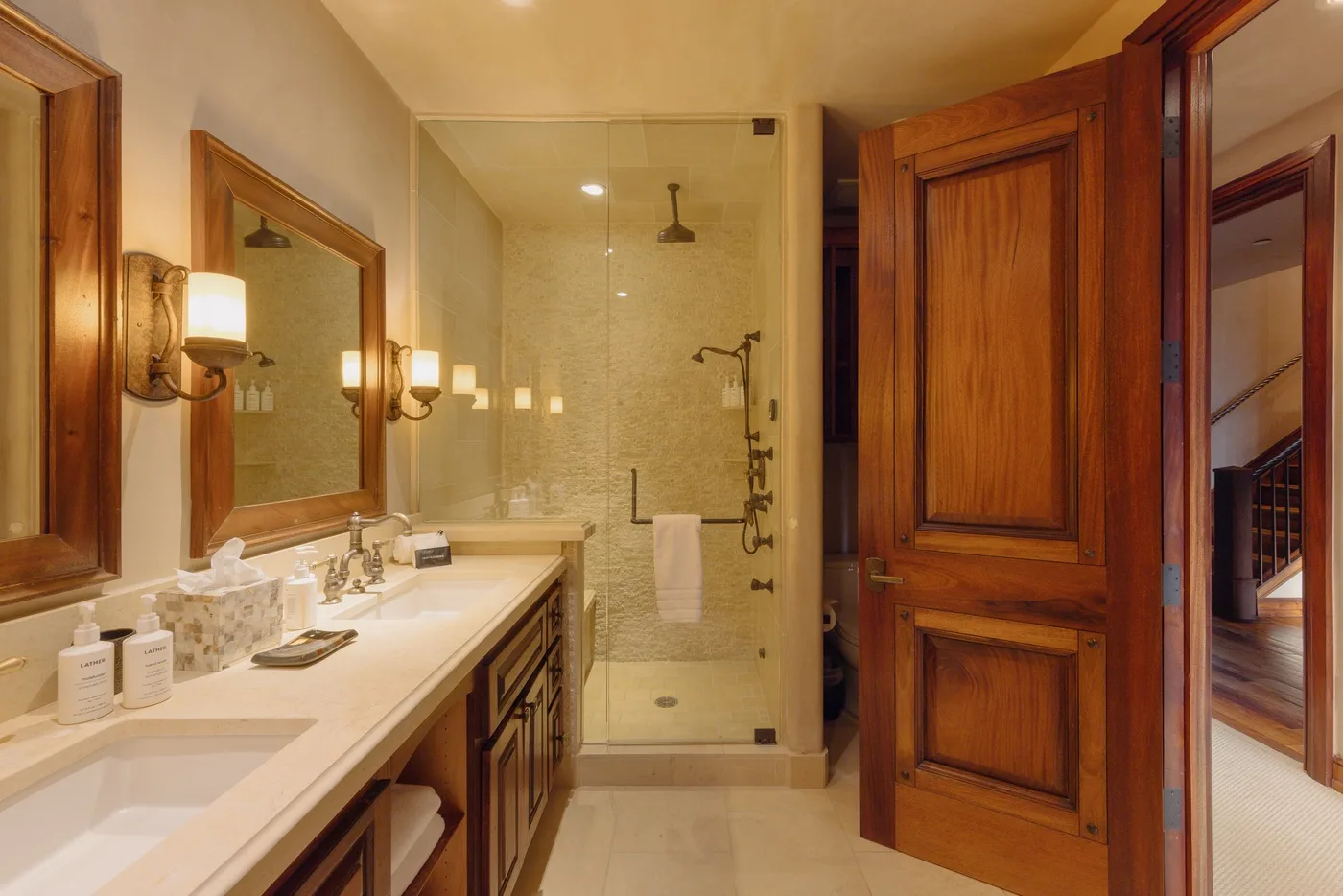 A bathroom with a long vanity and a glass shower at the far end.