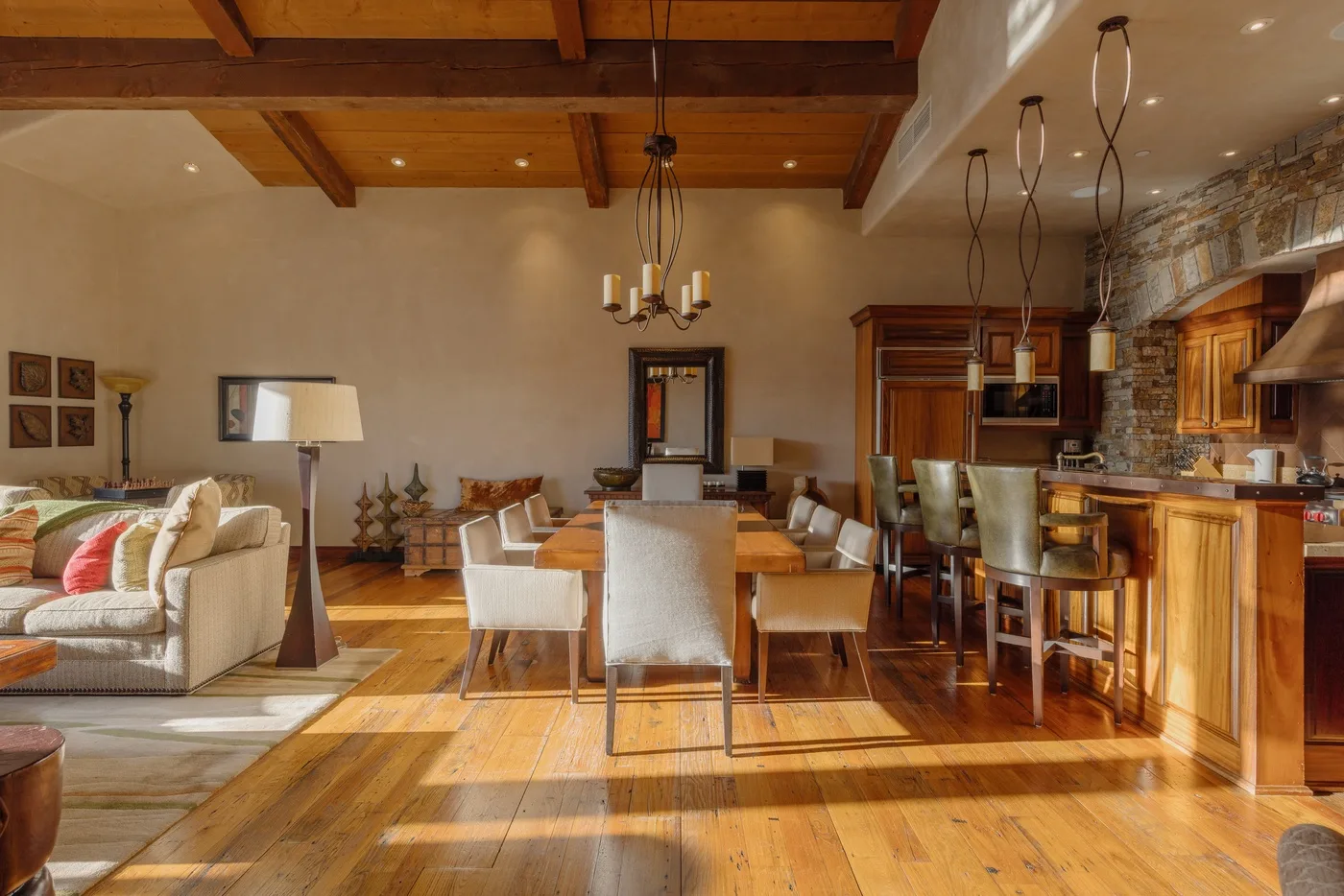 An open-plan living and dining area with a kitchen and exposed wooden beams.