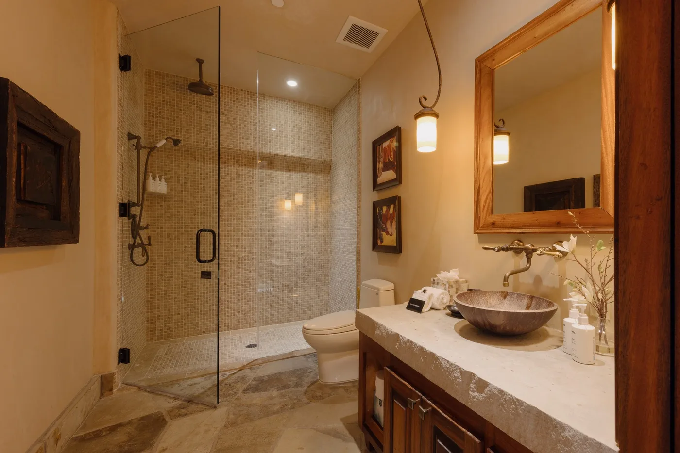 A bathroom with a glass shower, toilet, and vanity with a basin.