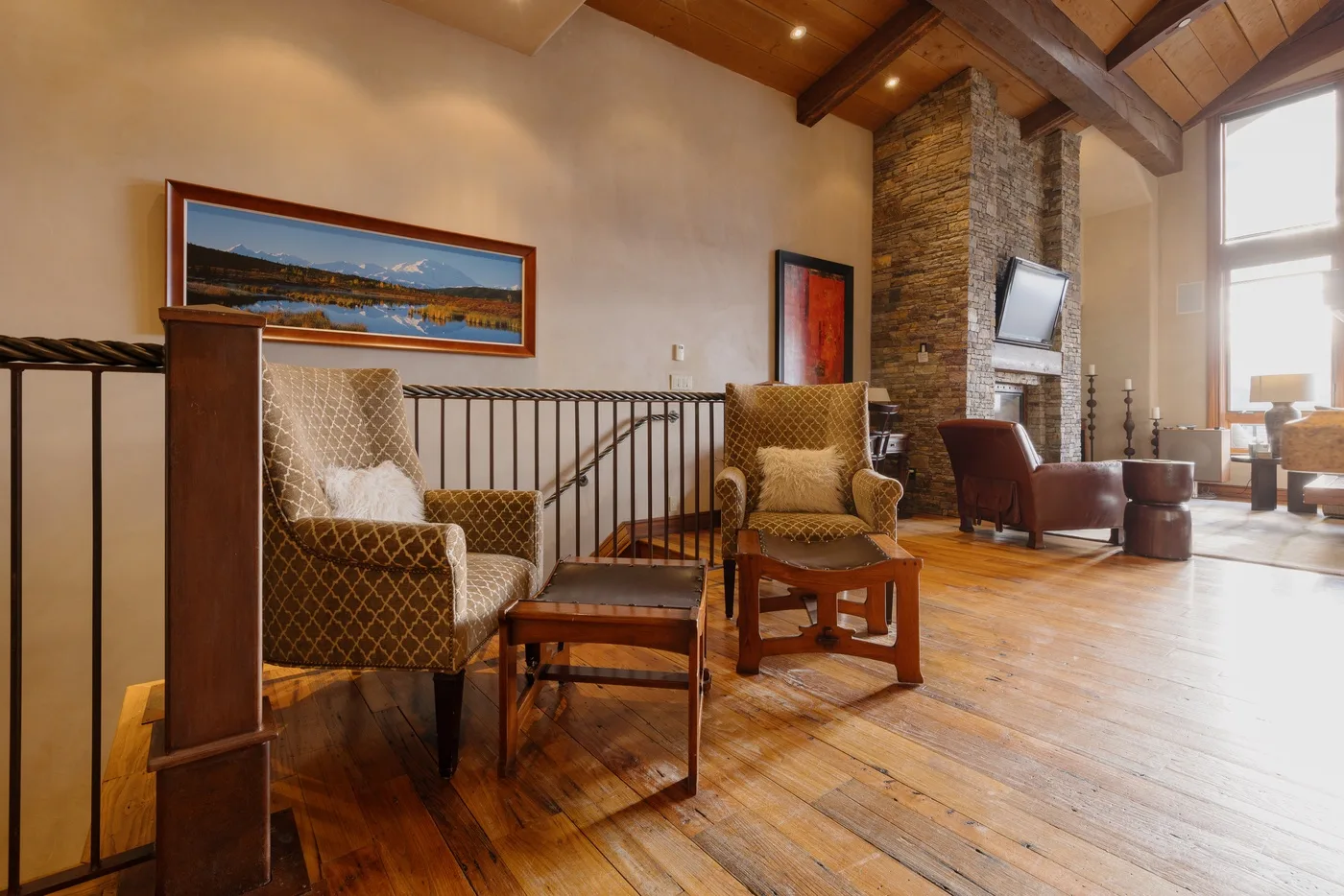 A loft-style living room with seating beside a stone fireplace.