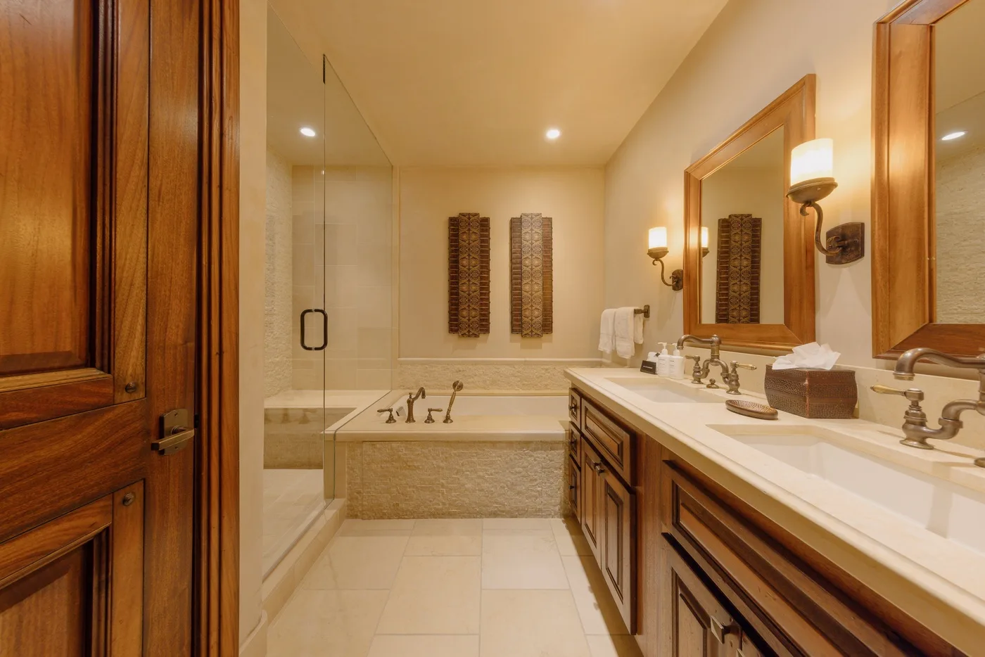 A bathroom with a bathtub, glass shower, and long vanity.