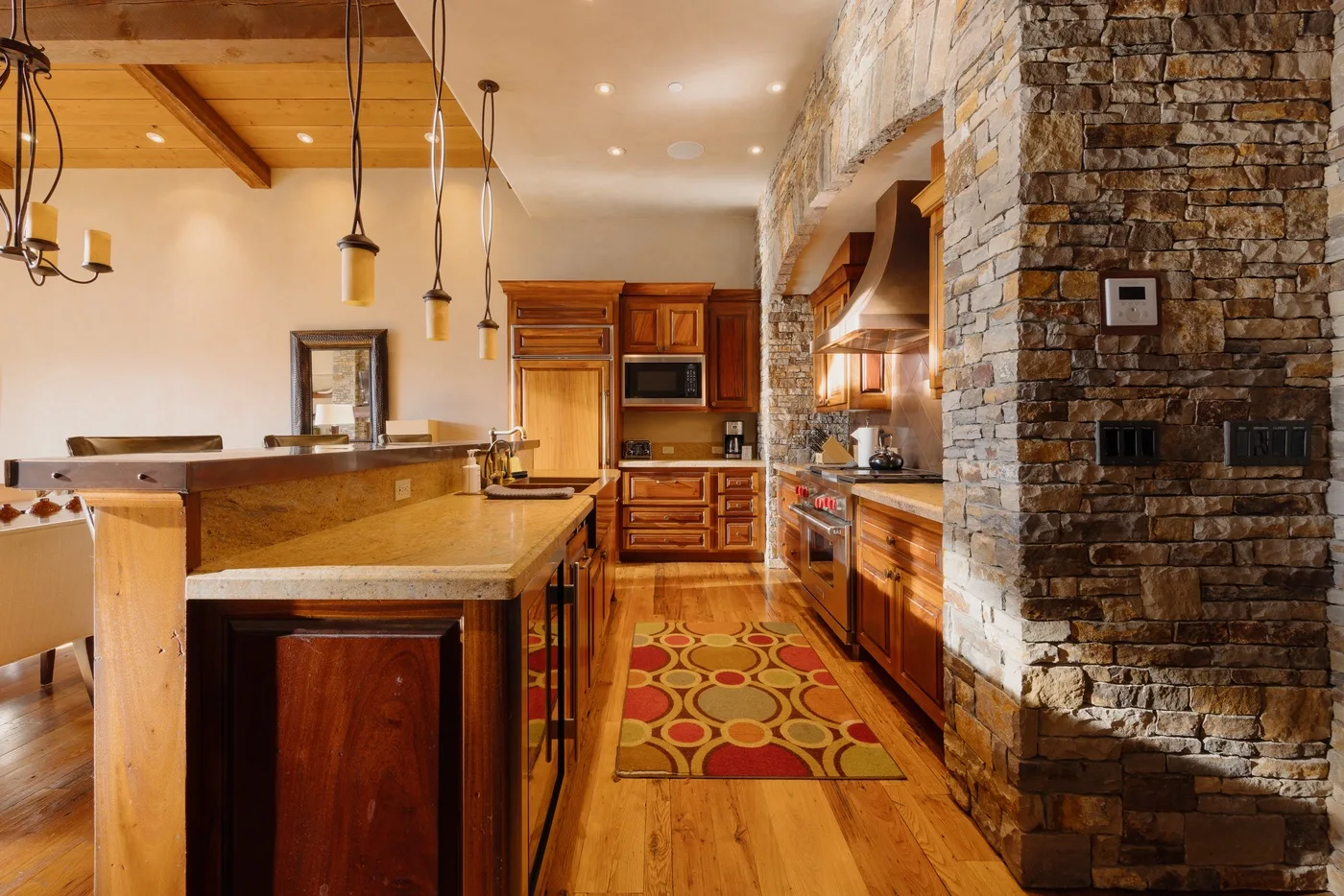 A warm kitchen with wooden cabinetry, a long island, and a patterned runner rug.