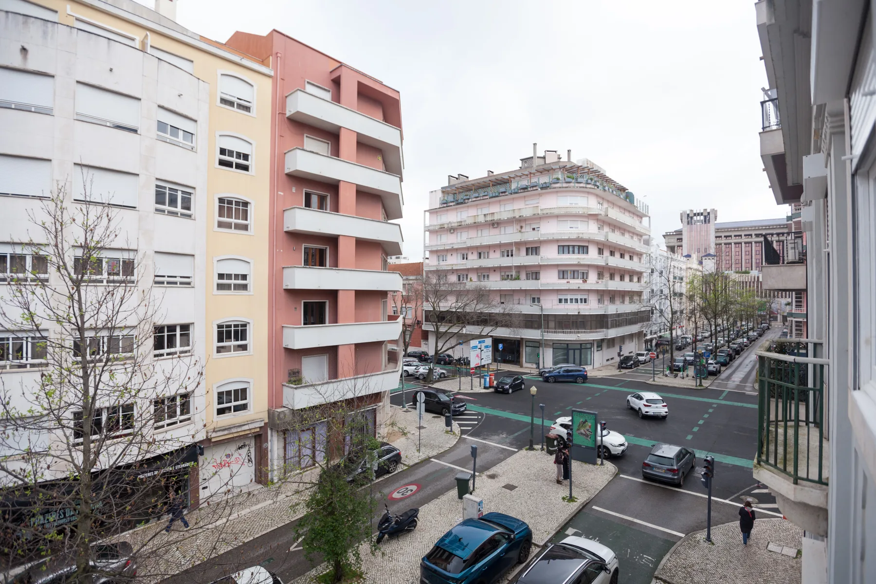 Urban street intersection with mid-rise apartment buildings and parked cars.