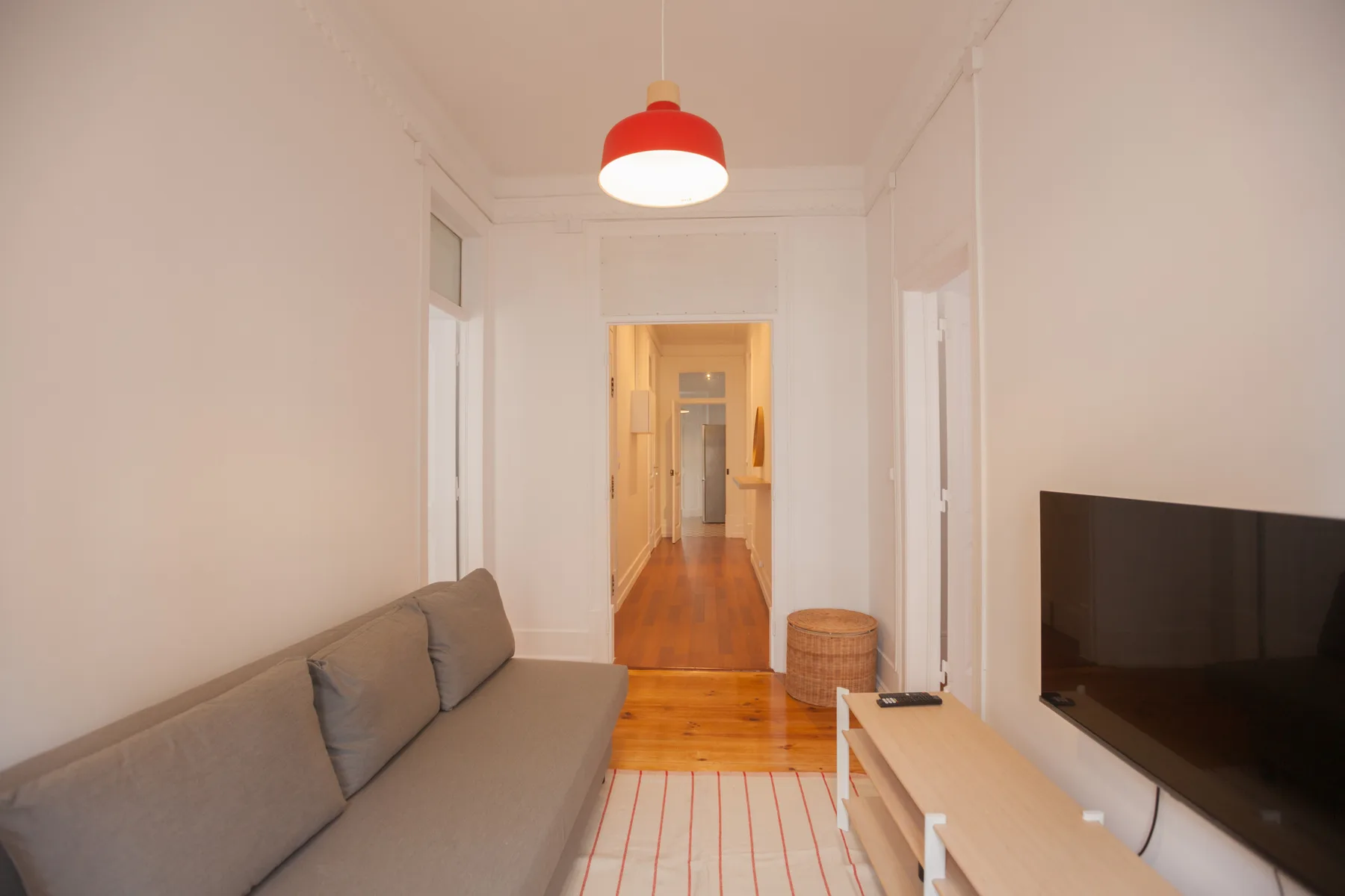 A living room with seating, a television, and a hallway beyond.