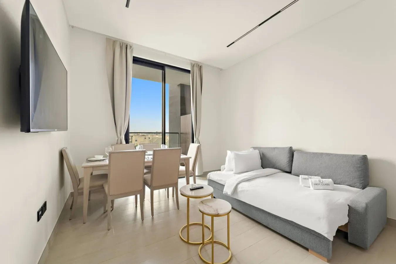 A bright living and dining area with a sofa and table beside a large window.