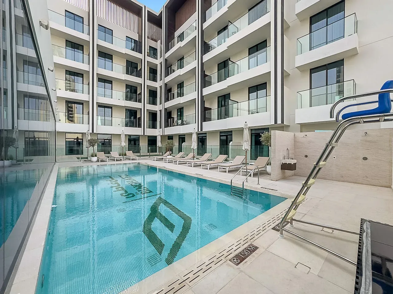 A courtyard swimming pool sits beside a modern multi-story building.