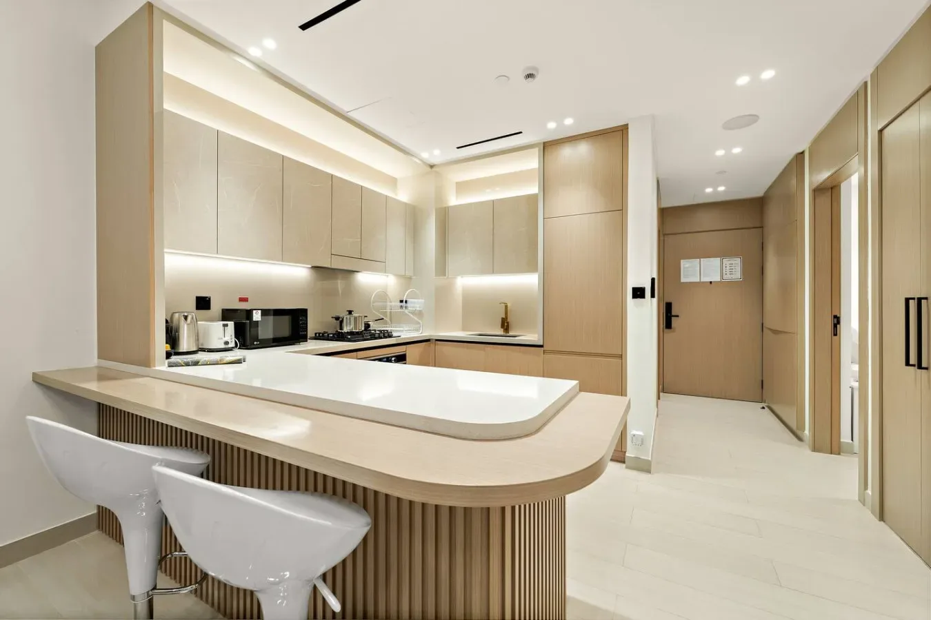 A bright modern kitchen with a long counter and white seating.