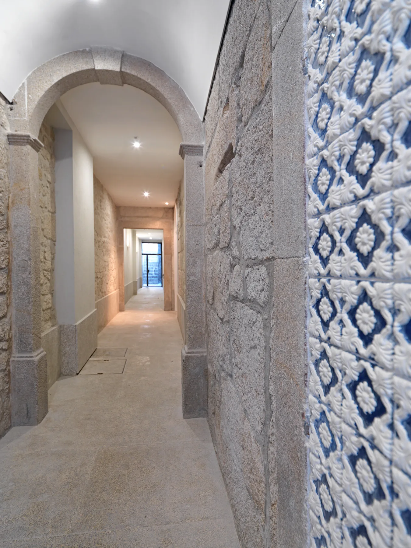 Un pasillo de piedra con un arco y azulejos estampados azules y blancos.