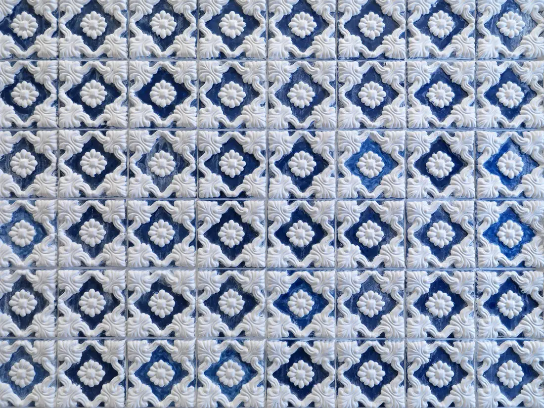 Vista cercana de una pared cubierta de azulejos estampados azules y blancos.