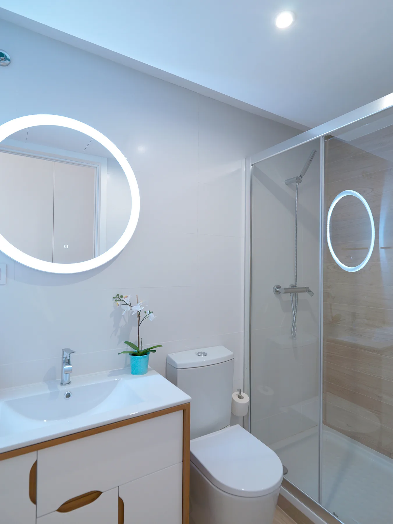 Un baño luminoso tiene lavabo, inodoro y ducha de cristal.