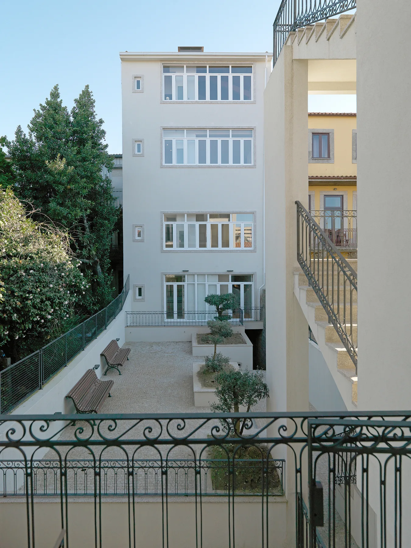 Un patio exterior con caminos pavimentados, bancos y edificios de apartamentos alrededor.