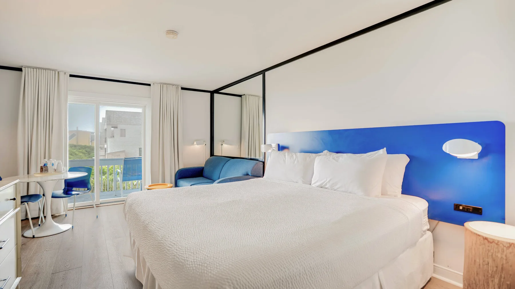 Un dormitorio luminoso con una cama grande, cabecero azul y ventana.