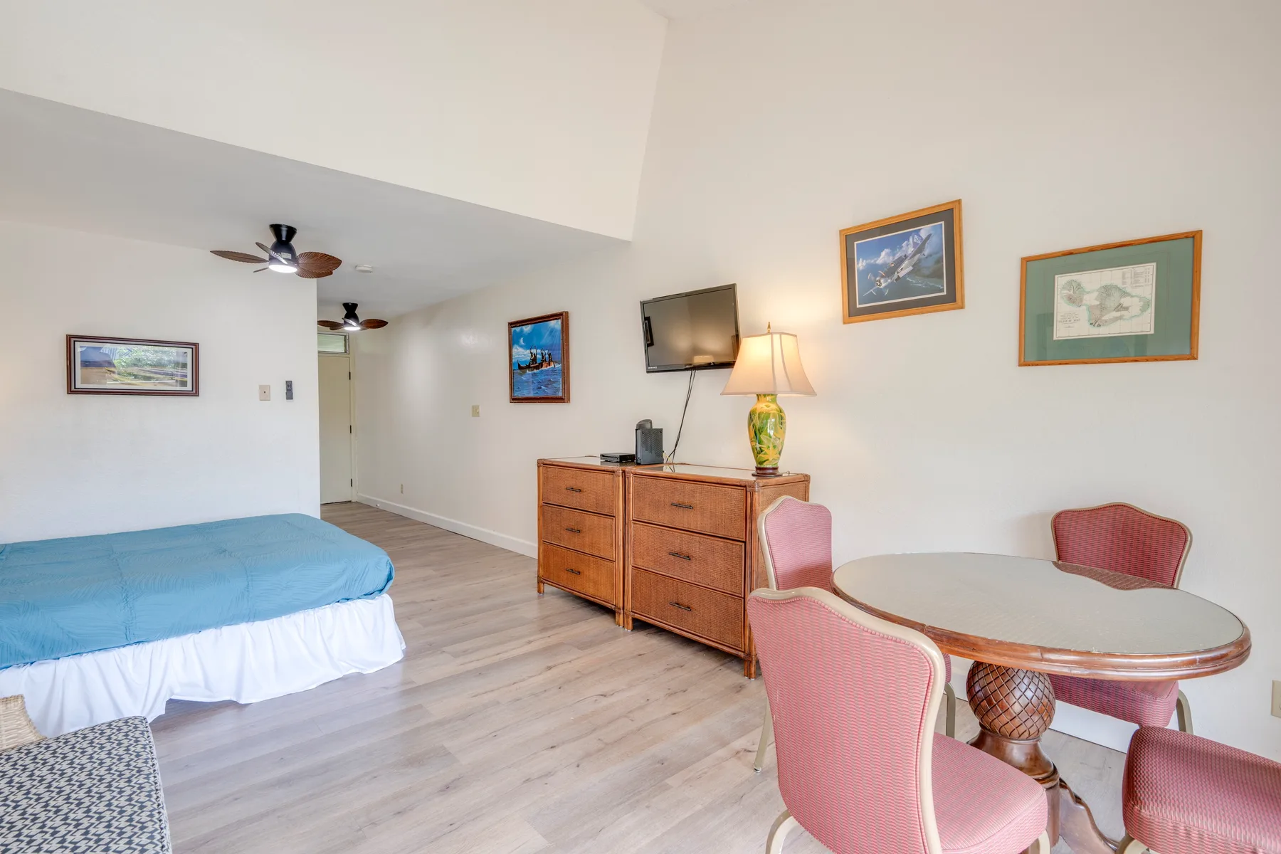 Un dormitorio con una cama, una cómoda y una pequeña zona de comedor.