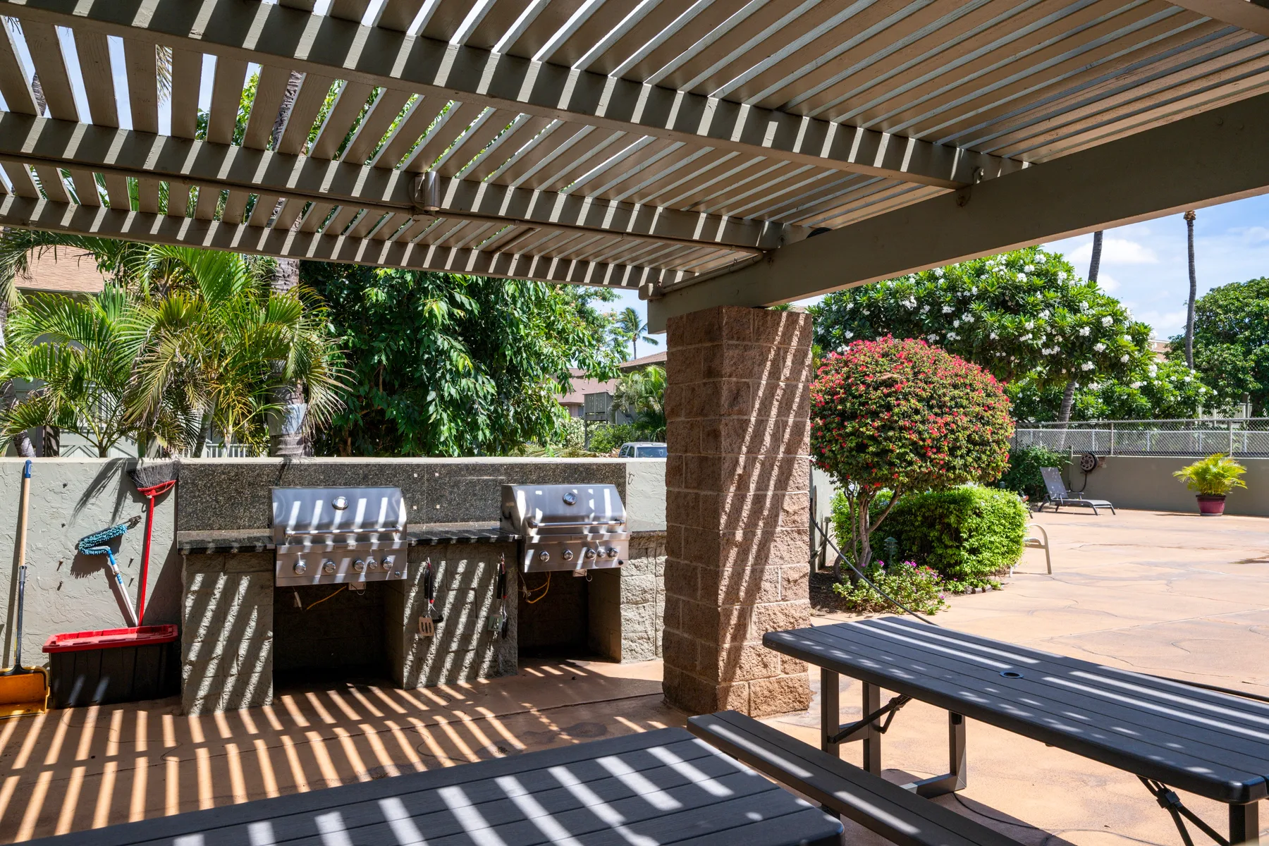 Un patio exterior cubierto con parrillas integradas, asientos y una pérgola.