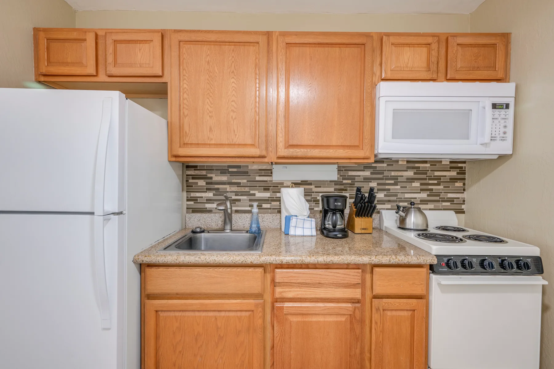 Una cocina con armarios de madera, un refrigerador y una encimera.