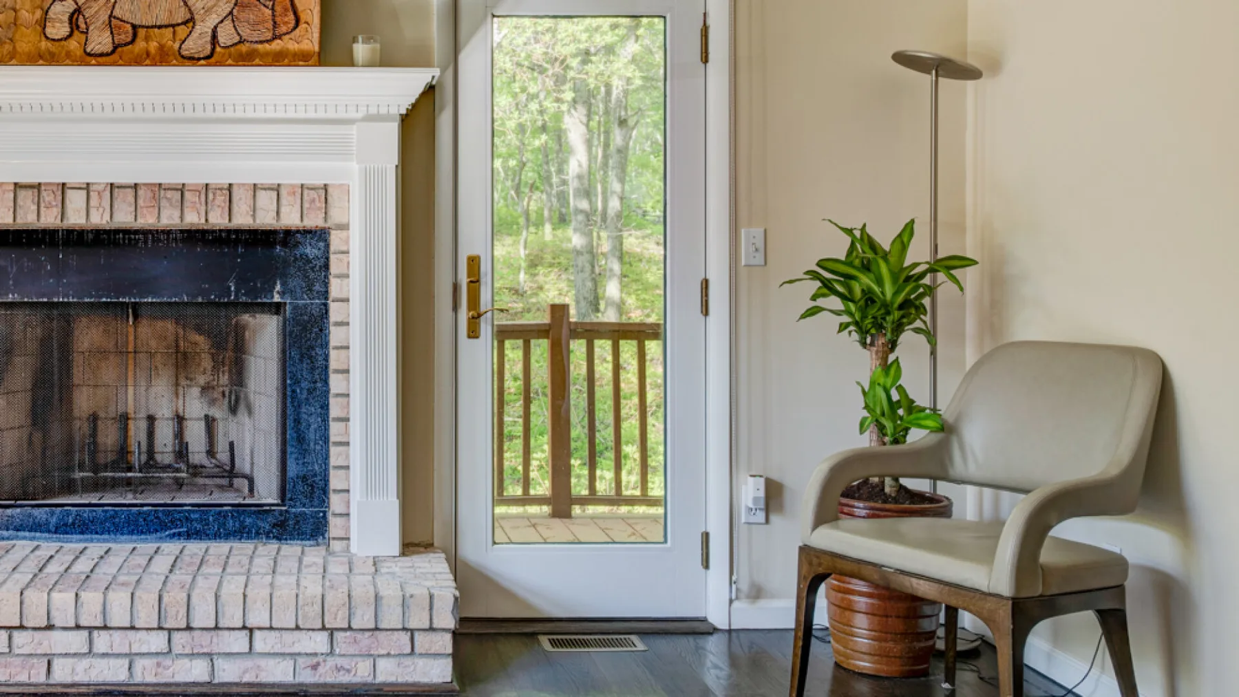 A living room features a brick fireplace, glass door, and a potted plant beside seating.