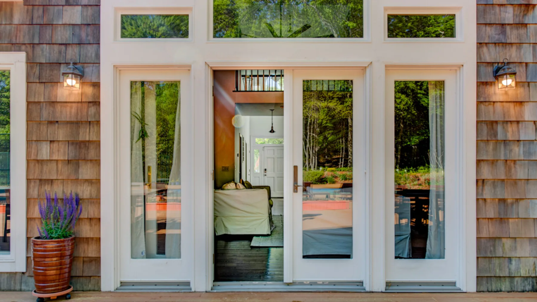 A house entrance with tall windows and a view of trees outside.