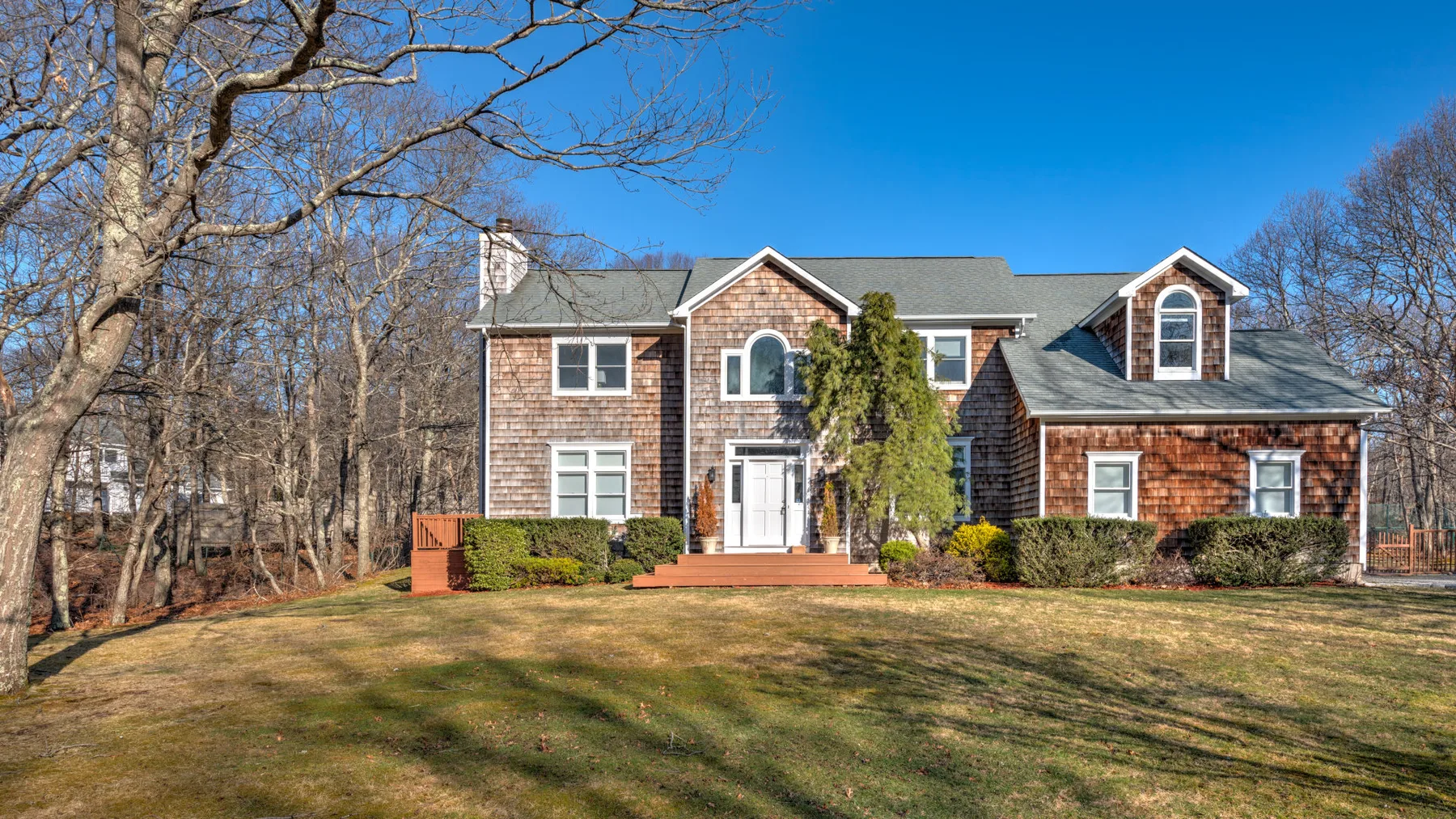A large house stands behind a broad lawn, with leafless trees nearby.