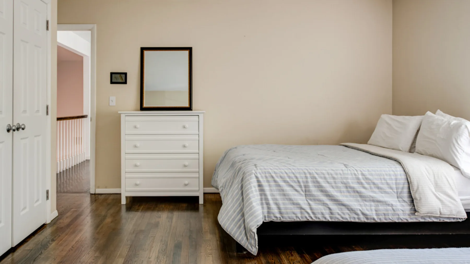 A bedroom with a bed, dresser, and mirror.