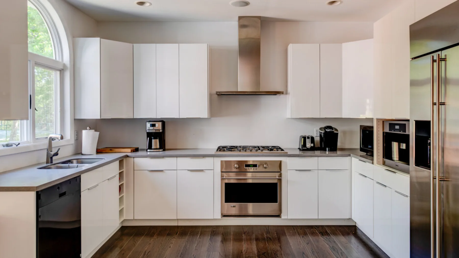 A bright modern kitchen with white cabinetry and stainless steel appliances.