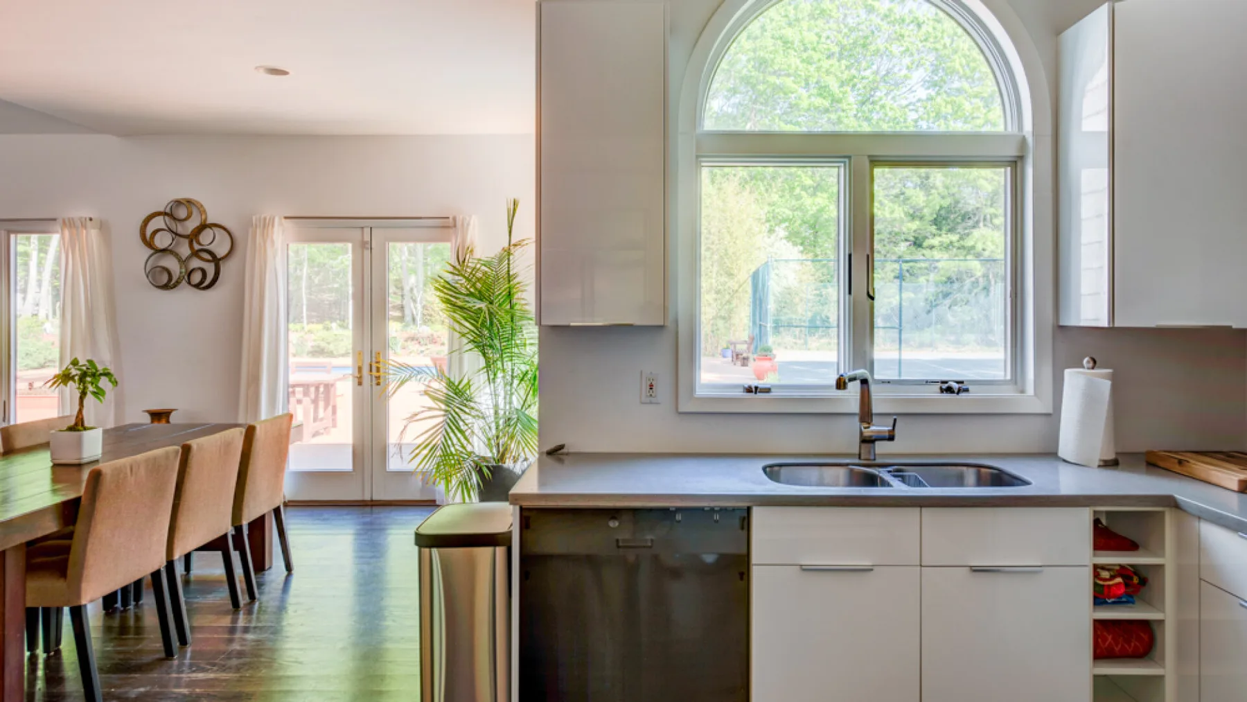 A bright kitchen and dining area features a large arched window.