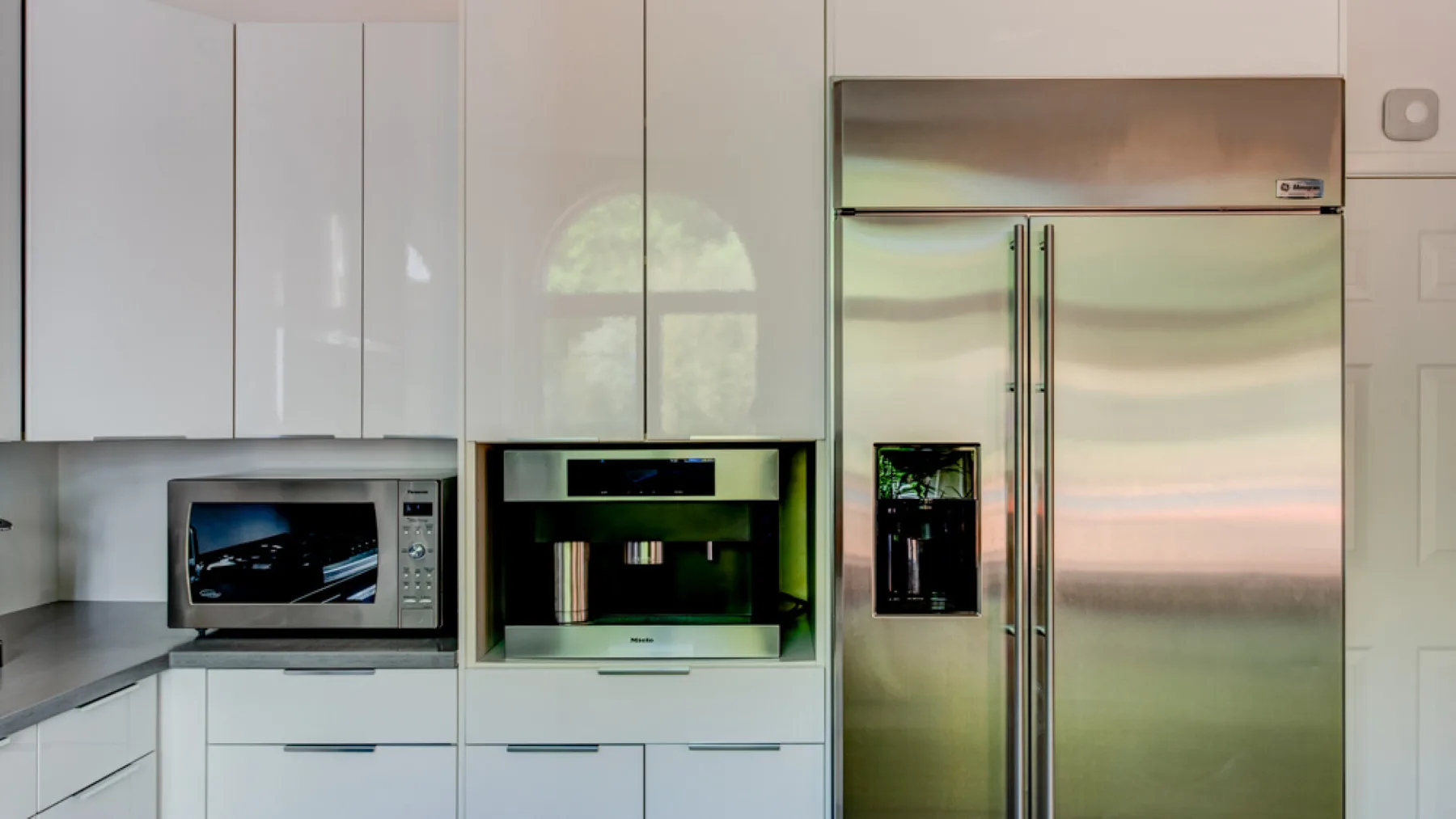 A modern kitchen with white cabinets and stainless-steel appliances.