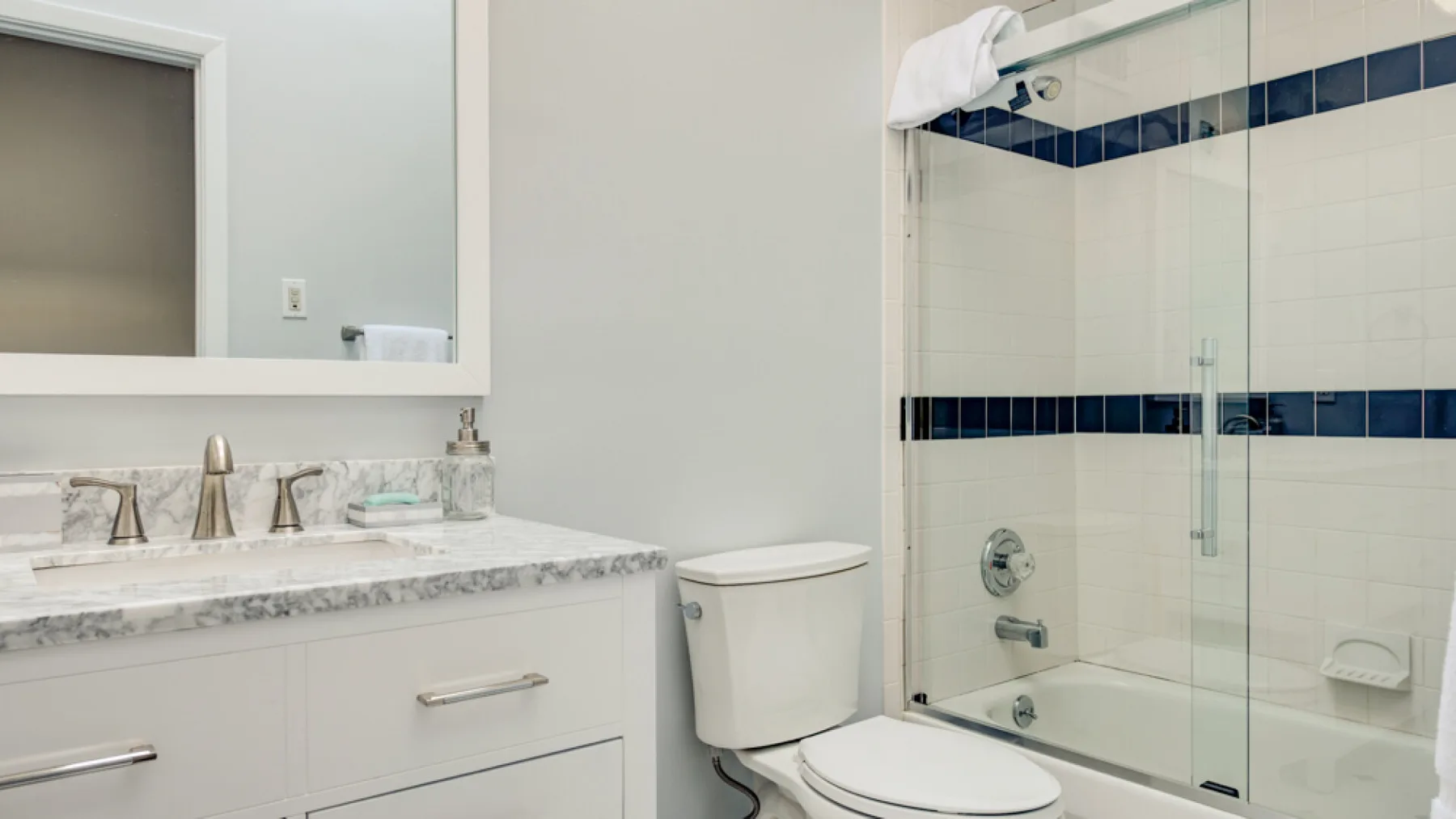 A bathroom with a sink vanity and a glass-enclosed shower.