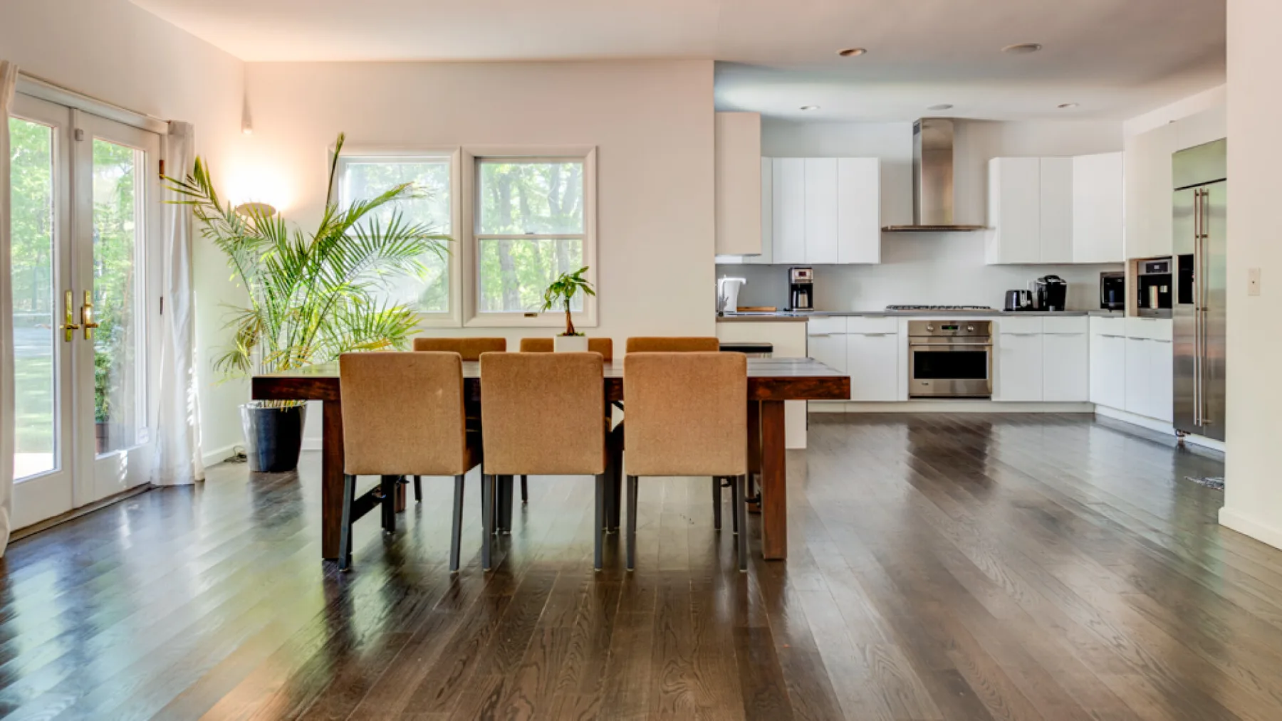 An open dining and kitchen area with a dining table and large windows.
