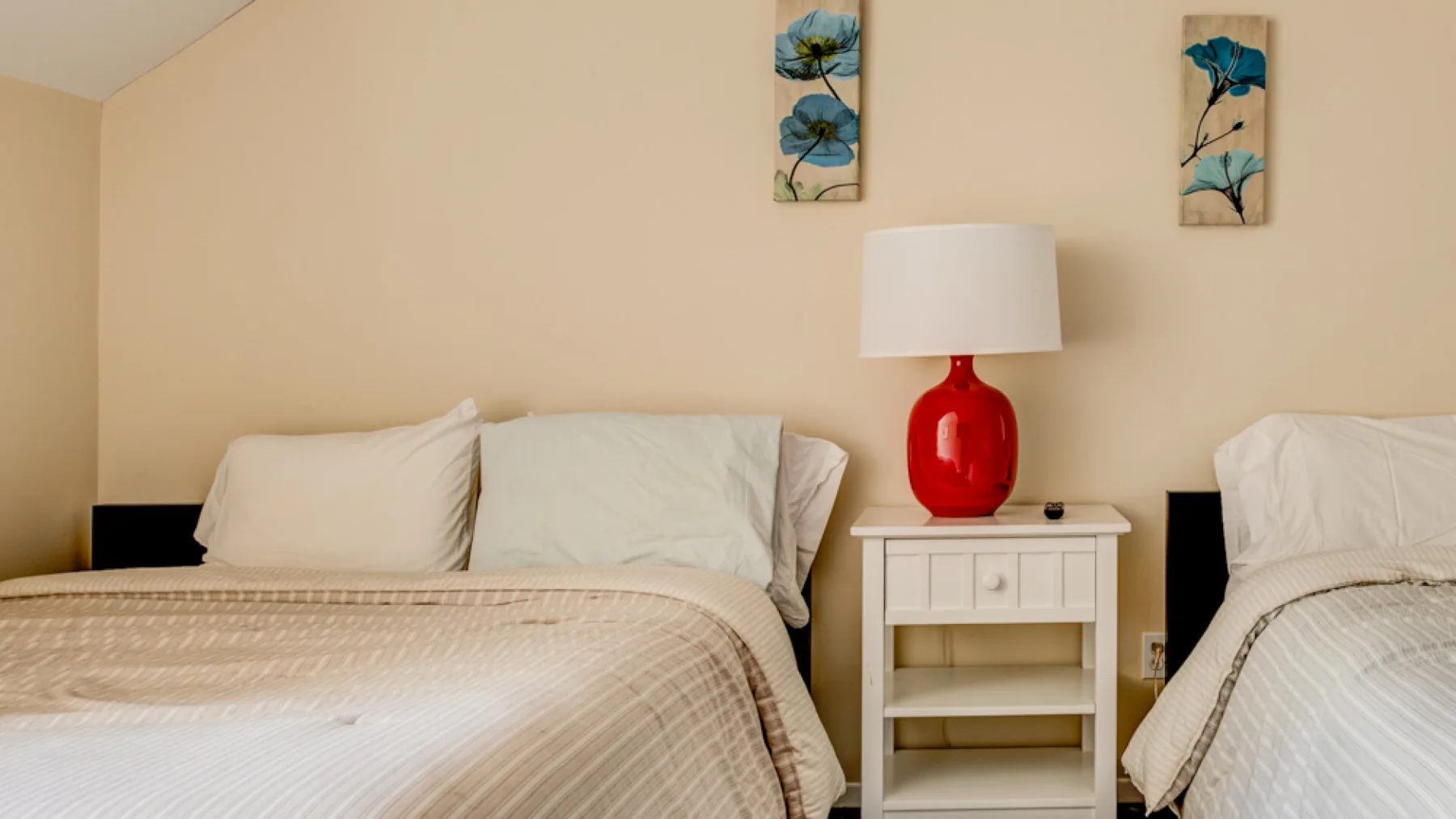 A bedroom with two beds and a small nightstand between them.