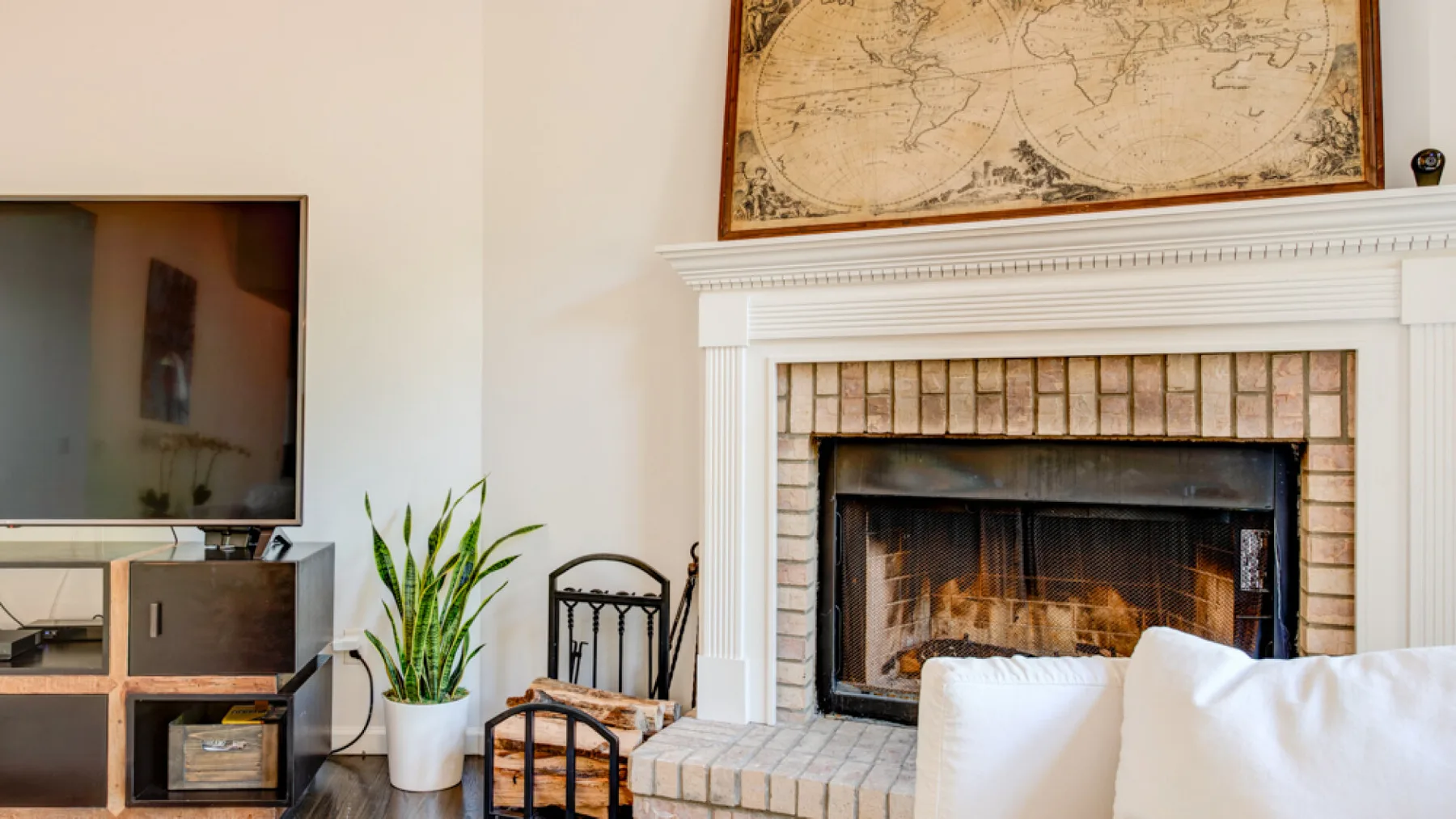 A living room features a fireplace, television, and potted plant.