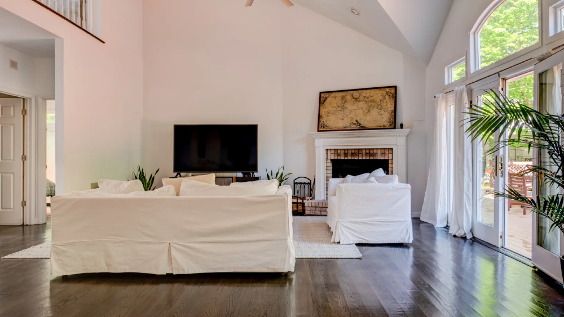 A bright living room with seating, a fireplace, and large windows.