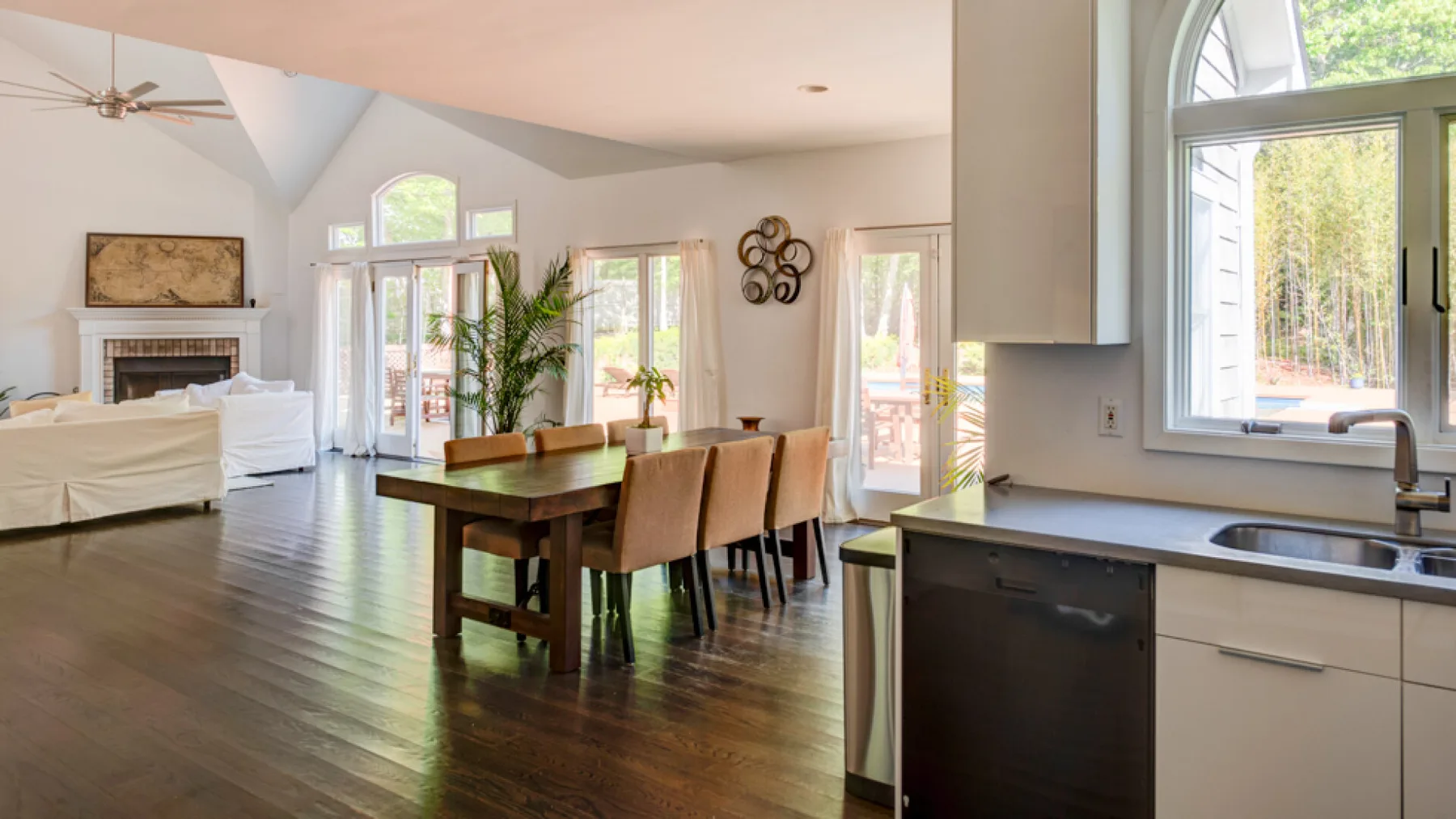 An open-plan living and dining area connects to a kitchen beside large windows.