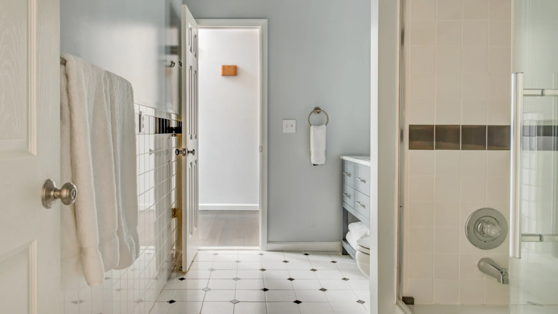 A bright bathroom with a tiled shower, towels, and a vanity.