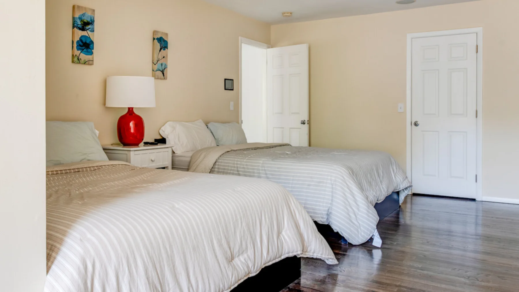 A bedroom with two beds dressed in light-colored bedding.