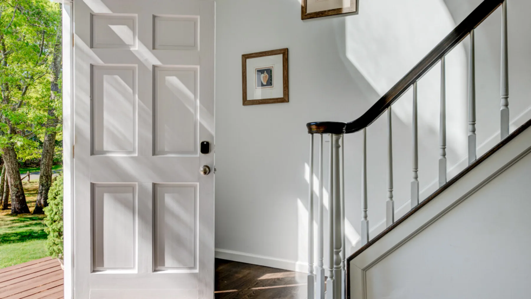 An entryway with an open front door and a staircase beside it.