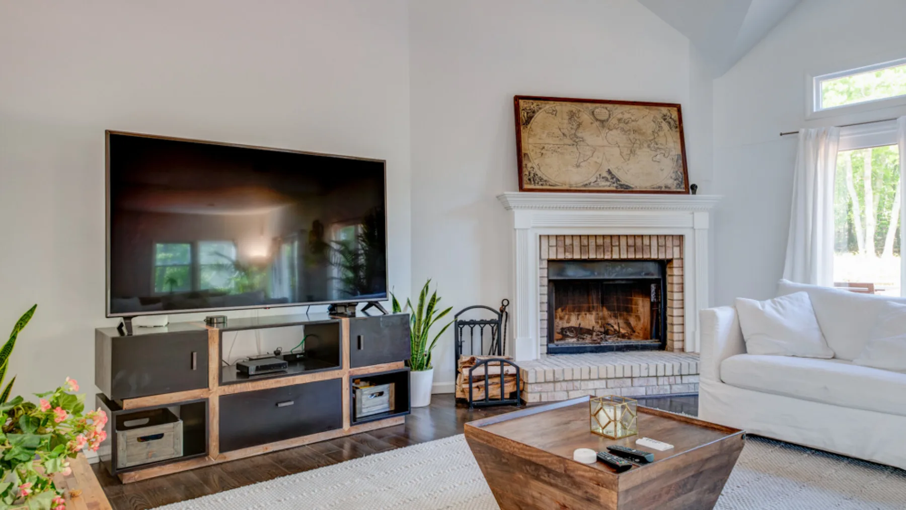 A bright living room with a fireplace, television, and seating.