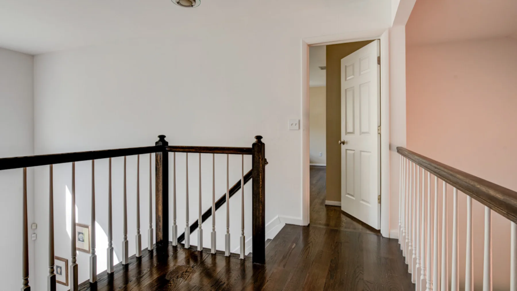 An upstairs landing with dark wood flooring and a railing around the stairwell.