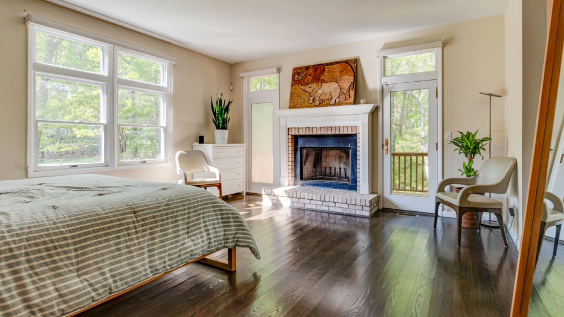 A bright bedroom with a bed, fireplace, and large windows.