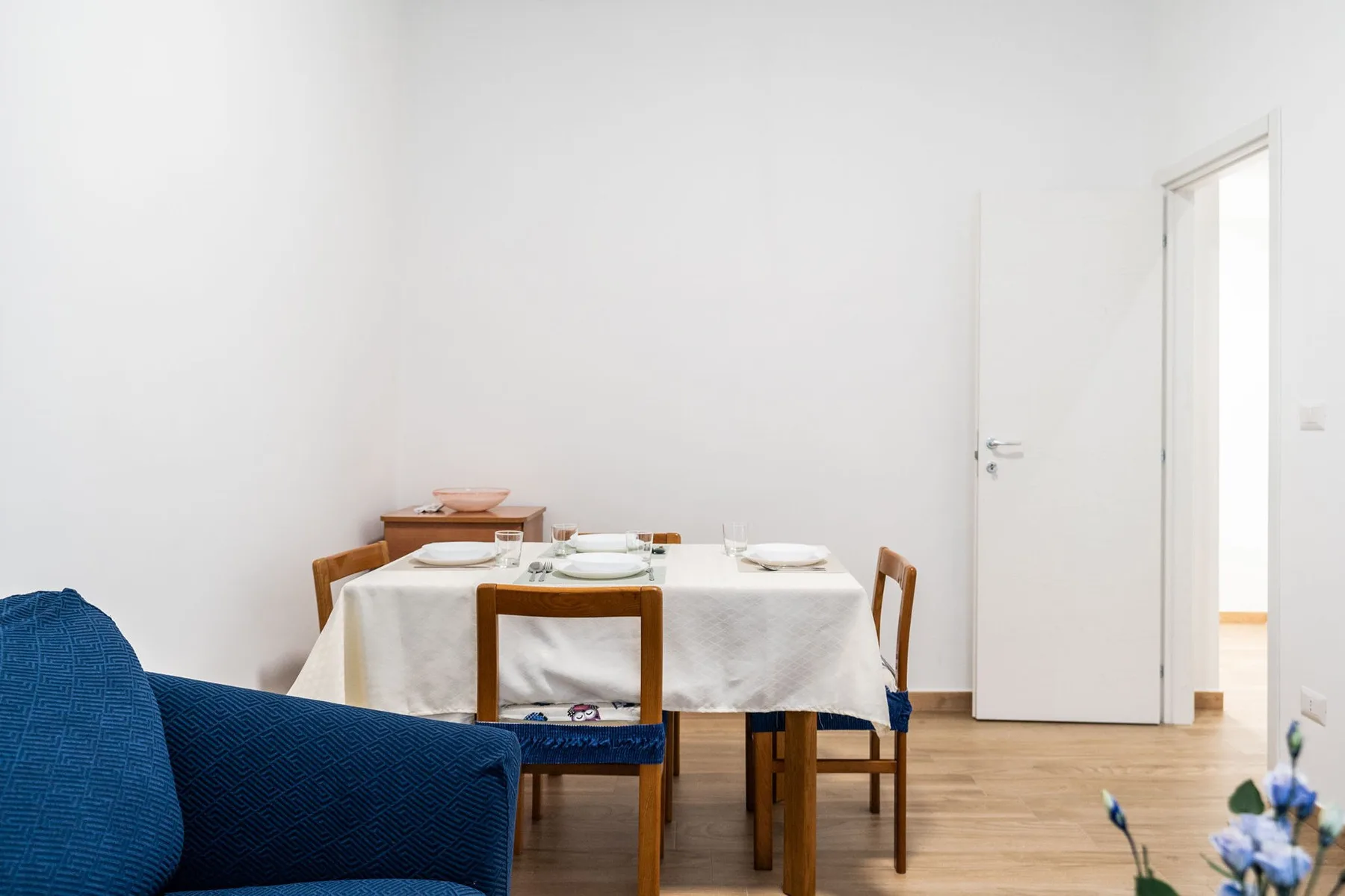 A dining area with a set table and blue seating in the foreground.