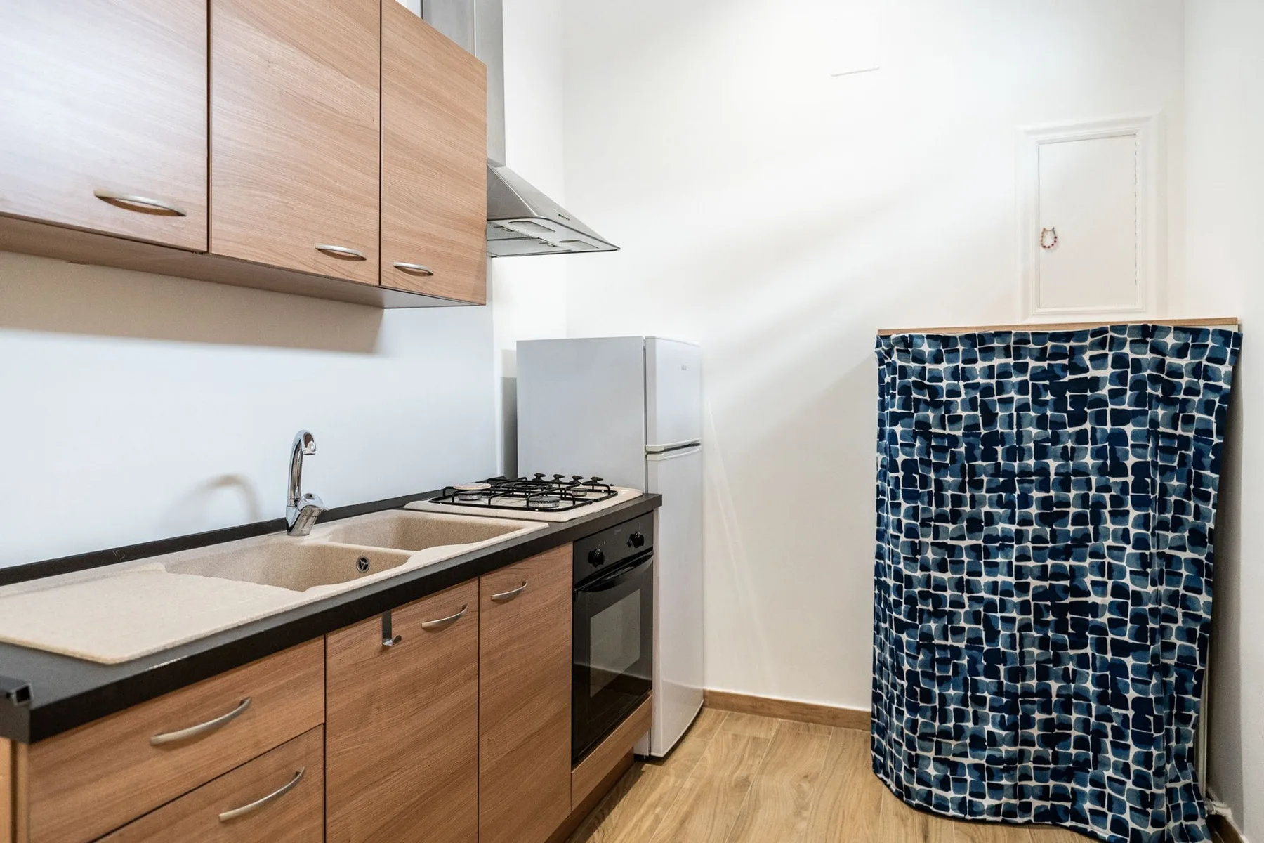 A compact kitchen with wood cabinets, a countertop, and a stove.