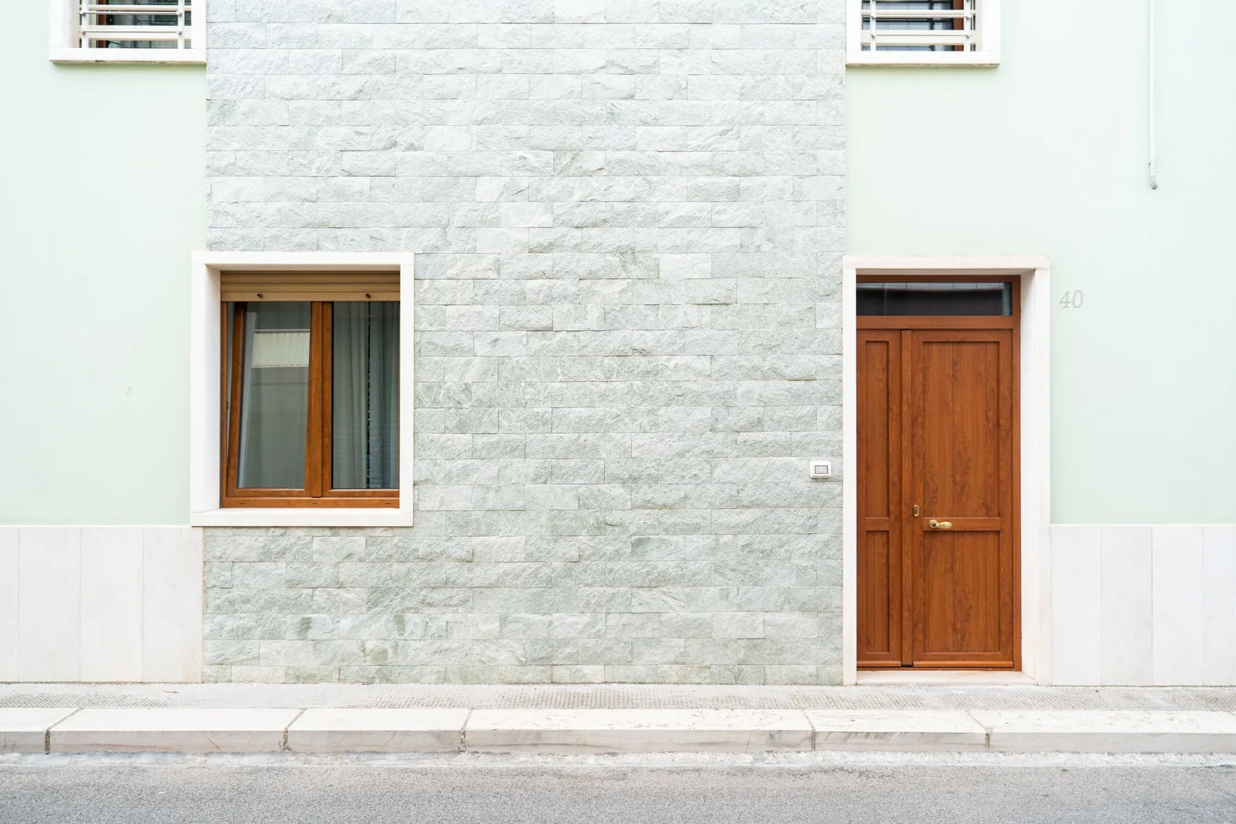 A building facade with a wooden door and a window set in pale stonework.