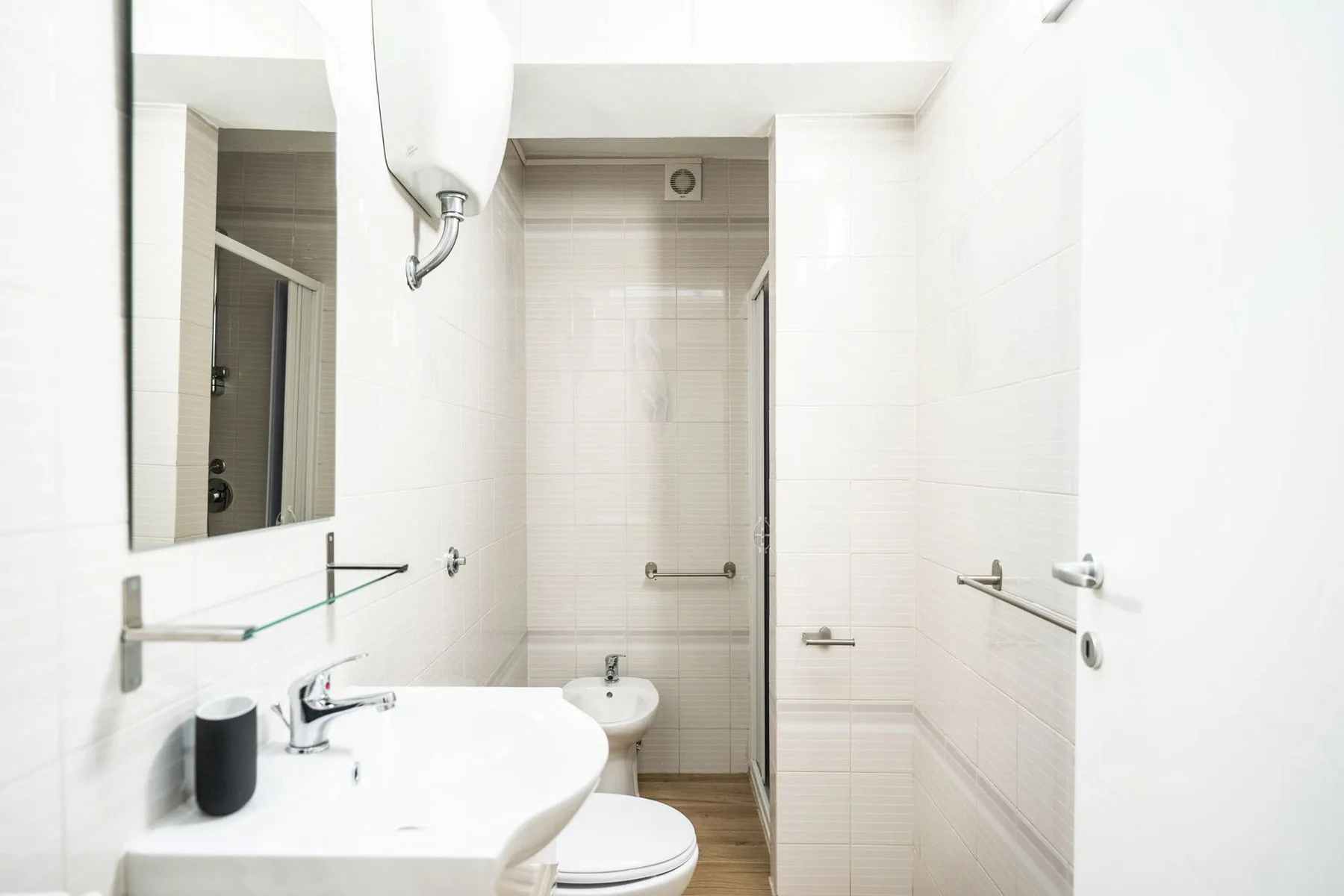A bright tiled bathroom with a sink, toilet, and shower.